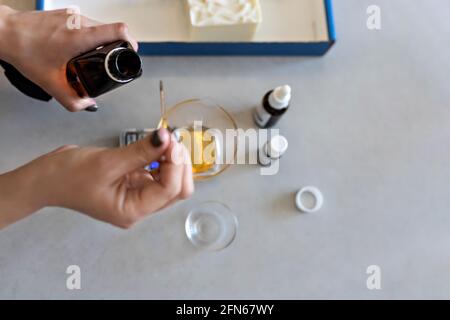 Eine Frau aus Seifenherstellung wiegt aromatische Öle für die Herstellung von Kosmetika im Küchenmaßstab. Spa im Haus. Kleinunternehmen. Stockfoto