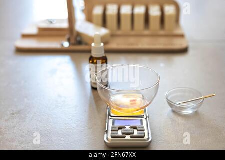 Ein Seifenhersteller wiegt aromatische Öle für die Herstellung von Kosmetika im Küchenmaßstab. Spa im Haus. Kleinunternehmen. Stockfoto