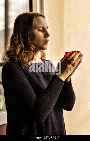 Eine junge Frau hält eine frisch geblasene Kerze in der Hand. Stockfoto