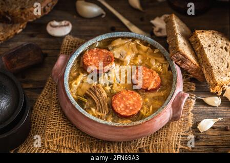 Weihnachts-Kohlsuppe in Keramikschale auf natürlichem Holzhintergrund. Stockfoto