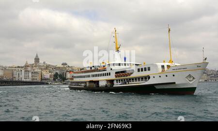 Die Fähren von Istanbul bringen Passagiere und Touristen durch die Stadt und ihren Stadtteil mit der Galata-Brücke und dem Turm im Hintergrund. Stockfoto