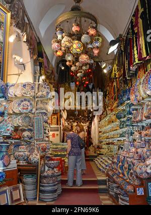 Zwei Damen suchen nach Schnäppchen in einem Souvenirladen im Großen Basar in Istanbul. Regale voller farbenfroher türkischer Gegenstände zum feilschen. Stockfoto