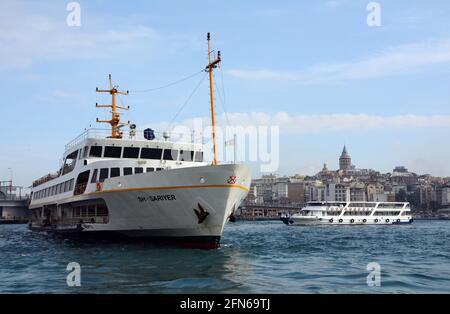 Die Fähren von Istanbul bringen Passagiere und Touristen durch die Stadt und ihren Stadtteil mit der Galata-Brücke und dem Turm im Hintergrund. Stockfoto