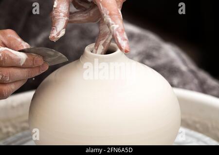 Potter / Töpfer Hände mit einem Metall Drehwerkzeug geschickt Hand Werfen eines Keramik geworfenen Ton Vase Topf auf einem Drehrad. England. VEREINIGTES KÖNIGREICH (123) Stockfoto