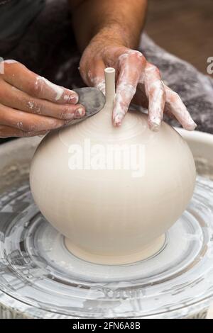 Potter / Töpfer Hände mit einem Metall Drehwerkzeug geschickt Hand Werfen eines Keramik geworfenen Ton Vase Topf auf einem Drehrad. England. VEREINIGTES KÖNIGREICH (123) Stockfoto