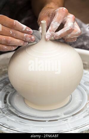 Potter / Töpfer Hände mit einem Metall Drehwerkzeug geschickt Hand Werfen eines Keramik geworfenen Ton Vase Topf auf einem Drehrad. England. VEREINIGTES KÖNIGREICH (123) Stockfoto