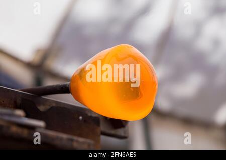 Ein Glasbläserrohr mit einem Gob (oder Blob) aus geschmolzenem Glas am Ende, ruht, rotiert, rollt und formt das Glas, arbeitet es auf dem flachen Metallmarver, bereit, vom Glasbläser geblasen zu werden. VEREINIGTES KÖNIGREICH (123) Stockfoto