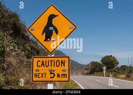 Achtung, Pinguine überqueren die nächsten 5 km! Warnschild an einer Küstenstraße an der Westküste der Südinsel Neuseelands. Stockfoto