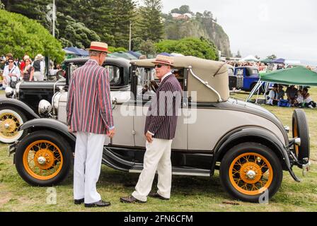 Stilvoll unterwegs: Zwei Herren, die im Stil der 30s gekleidet sind, nehmen an der jährlichen Feier während des Art déco-Wochenendes in Napier Teil und sprechen mit den Besitzern eines alten Ford Model A aus dem Jahr 1930. Stockfoto