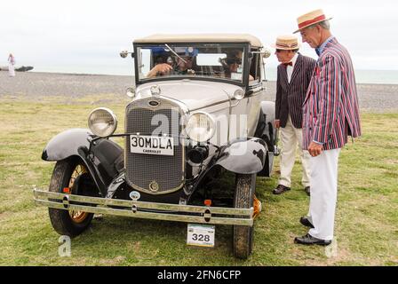 Stilvoll unterwegs: Zwei Herren, die im Stil der 30s gekleidet sind, nehmen an der jährlichen Feier während des Art déco-Wochenendes in Napier Teil und sprechen mit den Besitzern eines alten Ford Model A aus dem Jahr 1930. Stockfoto