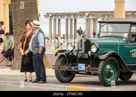 Stilvoll unterwegs: Ein Paar, das an der jährlichen Feier während des Art déco-Wochenendes in Napier teilnimmt, gekleidet im Stil der 30s Jahre neben einem Oldtimer von Chevrolet. Stockfoto