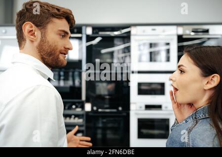 Junges Paar, das sich für einen neuen Elektroofen im Hypermarkt entscheidet Stockfoto