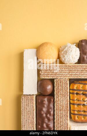 Bonbons, Kekse, Waffeln und Sumpflaibe auf gelbem Hintergrund in Nahaufnahme. Stockfoto