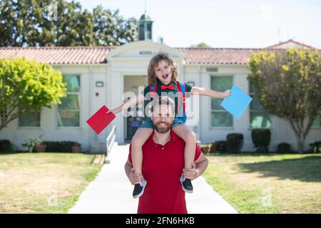 Vater Huckepack Fahrt unterstützt und motiviert Sohn. Kindererziehung. Kind geht zur Grundschule. Stockfoto