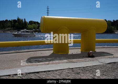 Helsinki / Finnland - 14. MAI 2021: Nahaufnahme eines metallischen Pollers am Hafen mit einer Yacht, die im Hintergrund über den Horizont segelt. Stockfoto