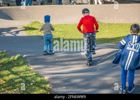 Kazan, Russland - 03. Oktober 2020: An einem sonnigen Herbsttag fahren Kinder im öffentlichen Park der Stadt mit einem Roller Stockfoto