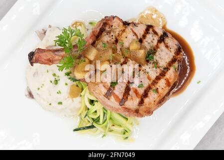 Blick von oben auf gegrilltes Schweinekotelett, serviert mit Kartoffelpüree und Pasta, um den herzhaften Appetit zu schwelgen. Stockfoto