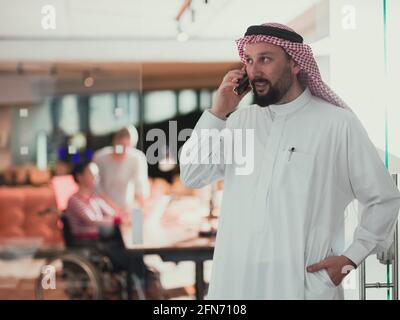 Nahöstlicher arabischer Geschäftsmann im Büro, der auf dem Smartphone spricht Vor seinem Team Stockfoto