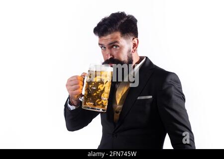 Porträt eines hübschen bärtigen Mannes, der ein Craft-Bier probiert. Stilvoller, hübscher Mann in schwarzem Anzug, der Bier trinkt. Schwule trinken Bier. Stockfoto