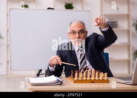 Alter Geschäftsmann Angestellter, der Schach am Arbeitsplatz spielt Stockfoto