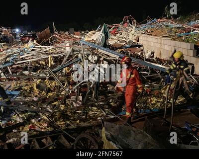 (210515) -- WUHAN, 15. Mai 2021 (Xinhua) -- das Foto, das am 15. Mai 2021 mit einem Mobiltelefon aufgenommen wurde, zeigt, dass Mitglieder des Rettungsteams nach einem Tornado im Bezirk Caidian in Wuhan, der zentralchinesischen Provinz Hubei, an den Trümmern eingestürzter Gebäude vorbeigehen. Nach Angaben von Regierungsbehörden wurden sechs Menschen nach dem Wirbelsturm am Freitagabend, der Wuhan in der zentralchinesischen Provinz Hubei umgab, als tot und 218 weitere verletzt bestätigt. Der Tornado mit 23.9 Metern pro Sekunde stürzten am Freitag um 8:39 Uhr durch den Caidian District, stürzten einige Baustellenschuppen und schnappten eine große Anzahl von Bäumen. (Xi Stockfoto