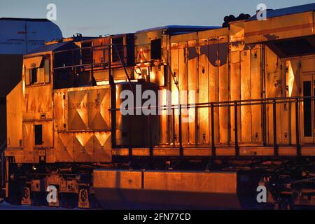 La Fox, Illinois, USA. Die Lokomotiven der Union Pacific Railroad, die einen Güterzug mit Auto-Zahnstange führen, reflektieren die untergehende Wintersonne. Stockfoto