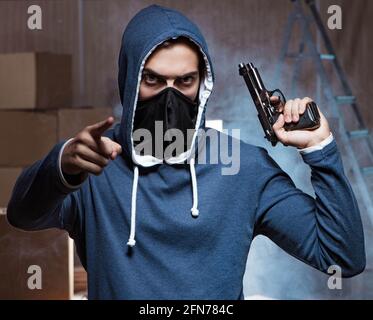 Die aggressive Manwith Pistole trägt Gesichtsmaske Stockfoto