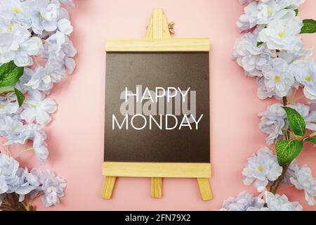 Happy Monday Text mit blühenden Blumen auf rosa Hintergrund Stockfoto