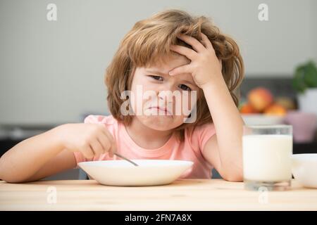 Unfokussierter kleiner Junge, der zum Mittagessen Suppe hat. Unglücklich kaukasischen Kind sitzen am Tisch in der Küche zu Hause haben keinen Appetit. Verärgert kleines Kind weigert sich zu essen Stockfoto