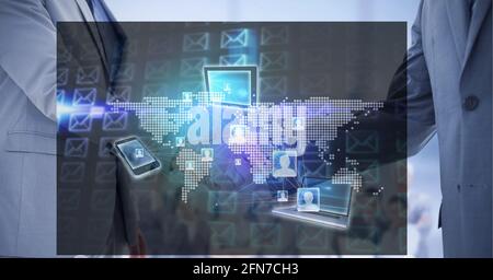 Netzwerk von Profilsymbolen und elektronischen Geräten auf der Weltkarte Gegen zwei Geschäftsleute, die sich die Hände schütteln Stockfoto