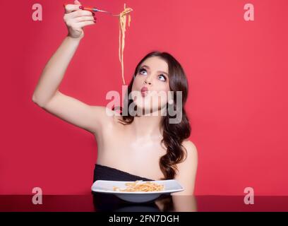 Mädchen isst italienische Pasta mit Tomatensauce. Frau mit Spaghetti. Bolognese schlängeln sich um die Gabel. Parmesankäse. Stockfoto