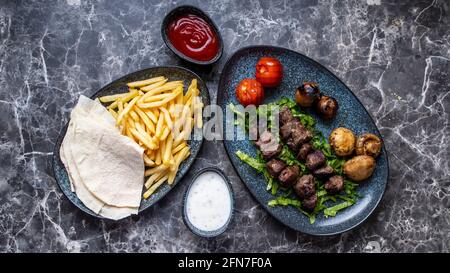 Shish Kebab bezieht sich auf gewürzte Fleischwürfel, die auf einem Spieß gegrillt werden.auf einem schwarzen weißen Marmortisch. Stockfoto