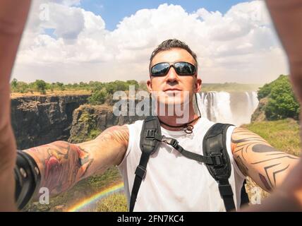 Moderner Hipster-junger Mann, der ein Selfie an den Victoria Waterfalls nimmt - Abenteuer Reise Lifestyle genießen Moment der Verbindung mit der Natur Stockfoto