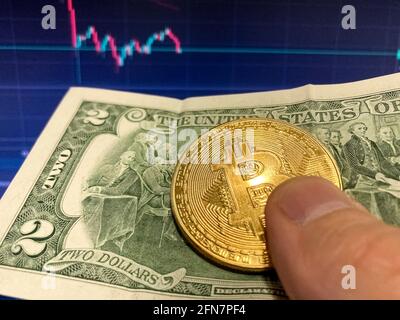 Bitcoin-Münze auf Papierrechnung zwei Dollar, USD - verschwommener Hintergrund. Der elektronische Zeitplan von Bitcoin, Volumen-Trades Stockfoto