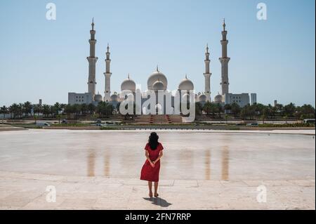 Frau genießt Aussicht Panoramablick auf die große Moschee Sheikh Zayed spiegelt sich im Wasser in Abu Dhabi, Vereinigte Arabische Emirate an einem sonnigen Tag. Große Moschee Stockfoto