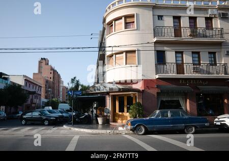 Cordoba, Argentinien - Januar 2020: Altmodisches blaues Auto, das an der Kreuzung in der Nähe des Cafés El Celta geparkt ist. Eingang zum Restaurant an der Ecke des Gebäudes Stockfoto