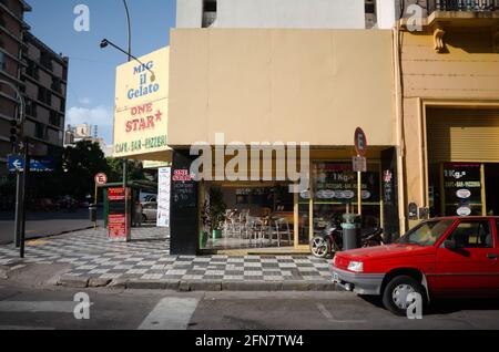 Cordoba, Argentinien - Januar 2020: Altes rotes Auto, das an der Straßenecke in der Nähe eines leeren Cafés mit dem Namen One Star Gelato Eis geparkt wurde. Kleine Cafebar Stockfoto