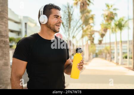 Latin Mann beim Joggen und Workout-Routine beim Hören von Musik Mit kabellosen Kopfhörern im Freien Stockfoto