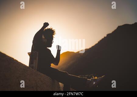 Afro-Mann, der Spaß beim Tanzen und Musikhören mit Kopfhörern hat Und Vintage Boombox Stereo bei Sonnenuntergang während der Ferien Stockfoto