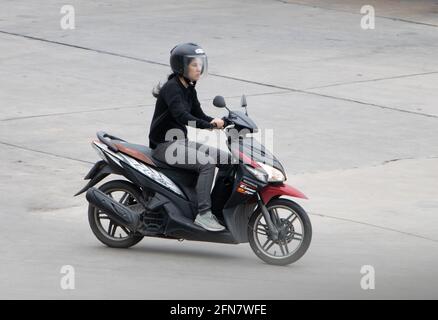 SAMUT PRAKAN, THAILAND, JULI 25 2020, EINE Frau mit Helm fährt ein Motorrad Stockfoto