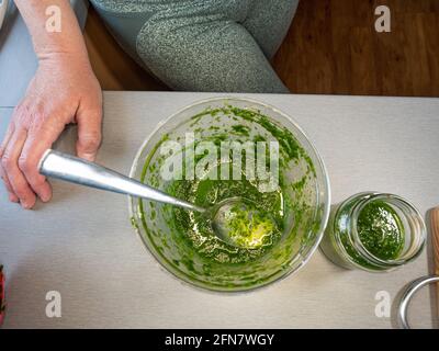 Frau, die frisches Bio-Pesto aus Frühlingsblättern von Bärlauch-Knoblauchkraut zubereitet. Hausgemachte Küche Stockfoto