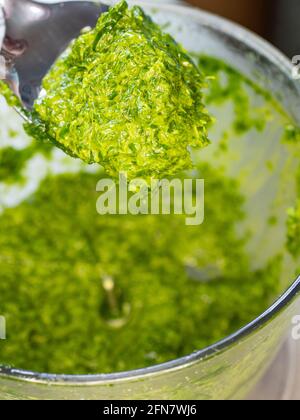 Bärlauch-Pesto aus Allium ursinum mit zerdrückten Cashewnüssen in einem Mörser. Zubereitung von Rohkost Stockfoto