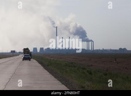 Betonplatten Straße mit Autos und Silhouette des Kraftwerks am Horizont. Grauer, wolkig. Pavlodar, Kasachstan. Stockfoto