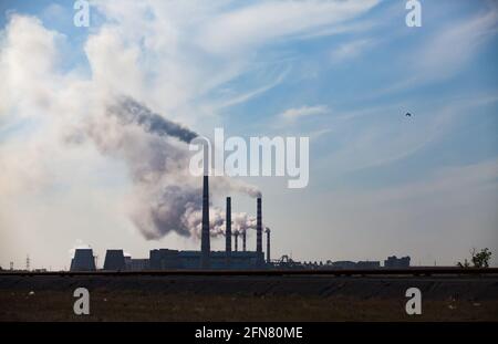 Silhouette des Pavlodar-Wärmekraftwerks mit Rauch vor blauem Himmel. Stockfoto