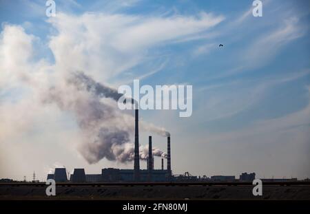 Silhouette des Pavlodar-Wärmekraftwerks mit Rauch vor blauem Himmel. Stockfoto