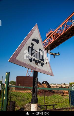Warnschild „Train“ gegen blauen Himmel. Deckenkran im Hintergrund. Stockfoto
