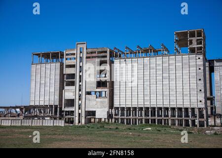 Veralteter sowjetischer Betonkornaufzug. Teilweise zerstörtes Gebäude. Blauer Himmel. Stockfoto