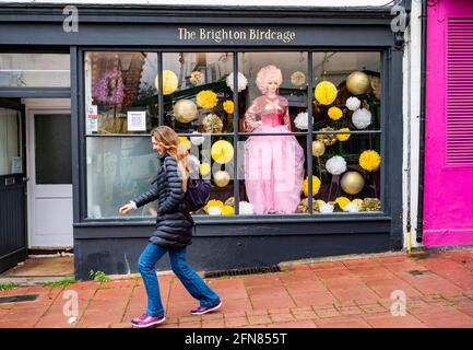 Brighton UK 15. Mai 2021 - EINE junge Dame stürzt die Straße entlang, vorbei am Brighton Birdcage Shop in Brighton, während heute in den meisten Teilen Großbritanniens feuchtes Wetter fegt : Credit Simon Dack / Alamy Live News Stockfoto