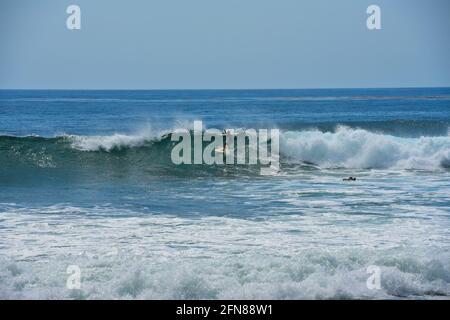 Landschaftlich reizvolle Küste mit einem Surfer, der auf einer Welle am Ufer des Oceanside Beach in San Diego, Kalifornien, USA, reitet. Stockfoto