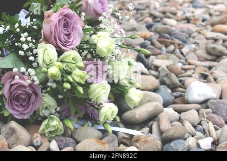 Hochzeit Bouquet mit violetten Rosen Blumen auf den Kieselgelen am Strand. Hochzeit Bouquet. Stockfoto